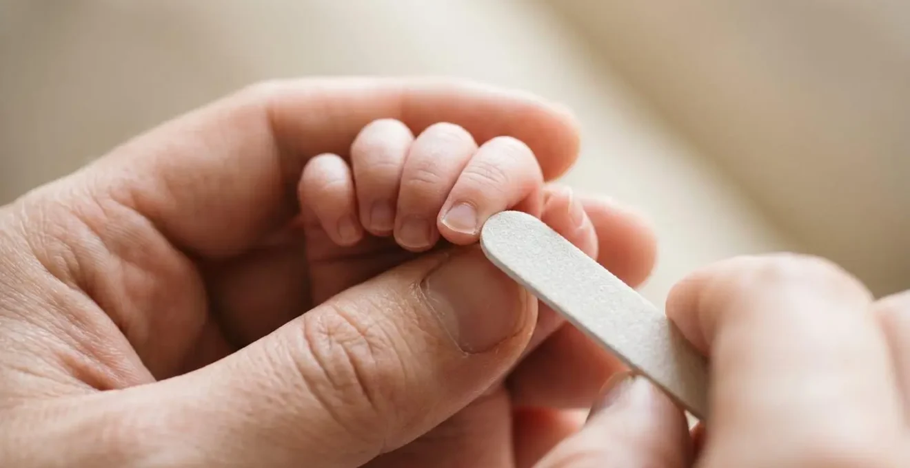 Extreme close-up of gentle baby nail care showing soft emery board technique on tiny infant fingers