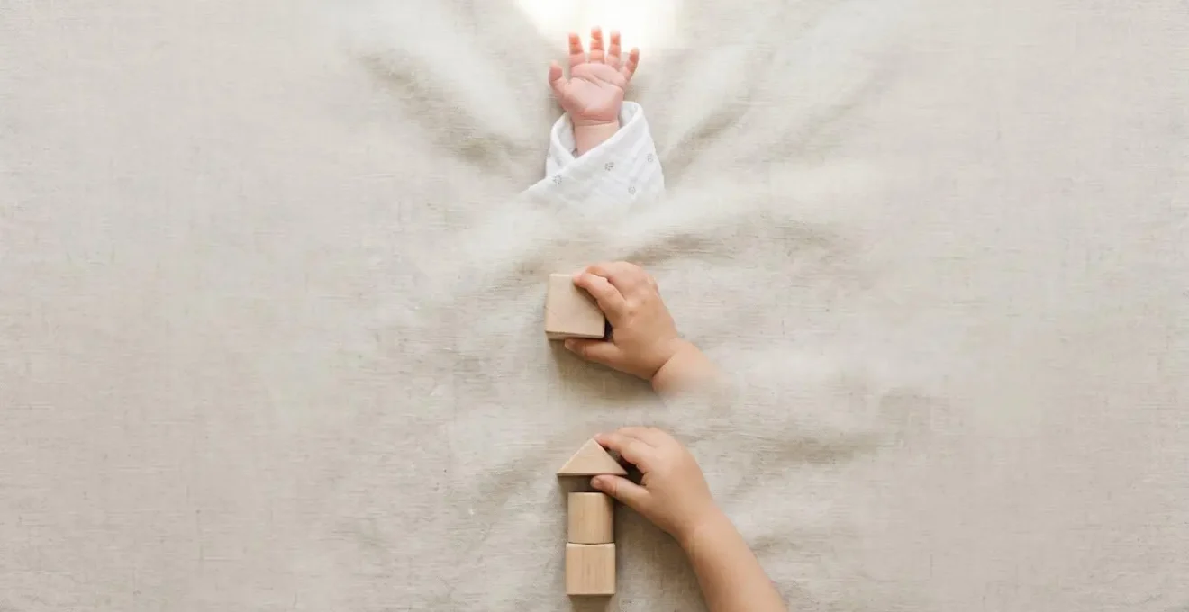 Visual representation of infant brain growth phases during the first two years, symbolized by a newborn hand, a hand grasping a block, and a toddler hand stacking shapes.