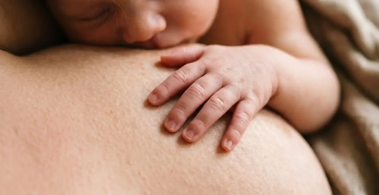 Close-up of newborn baby on mother's bare chest demonstrating natural thermoregulation through skin-to-skin contact