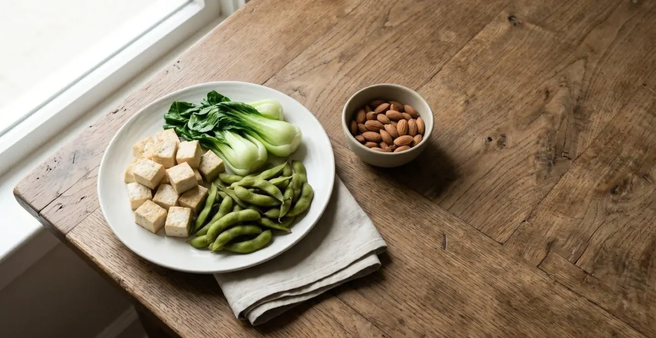 Wide shot of a minimalist meal spread featuring tofu, leafy greens, and legumes arranged on a clean wooden table