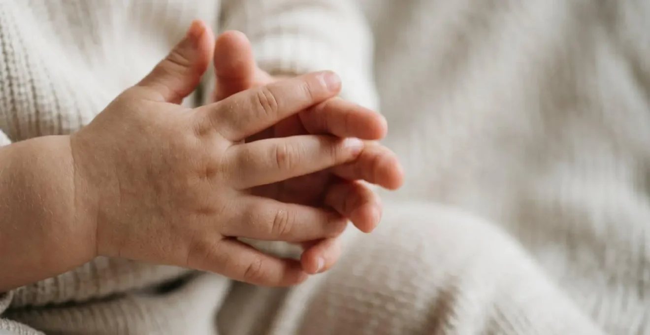 Close detailed view of toddler hands showing fidgeting behavior against soft neutral background